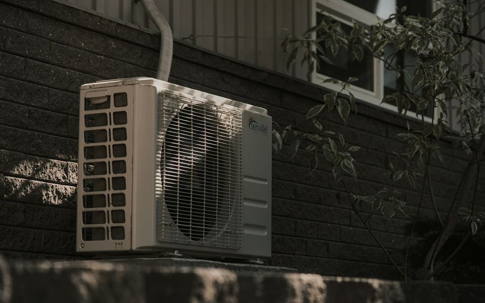 Outdoor air-conditioning condenser beside a brick home